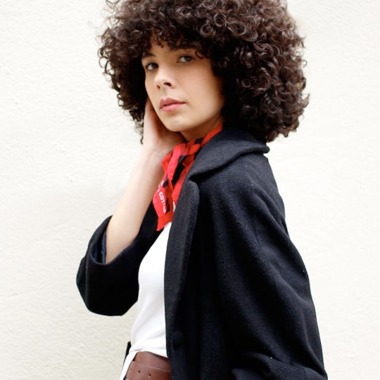 a young woman with curly hair looks at the camera